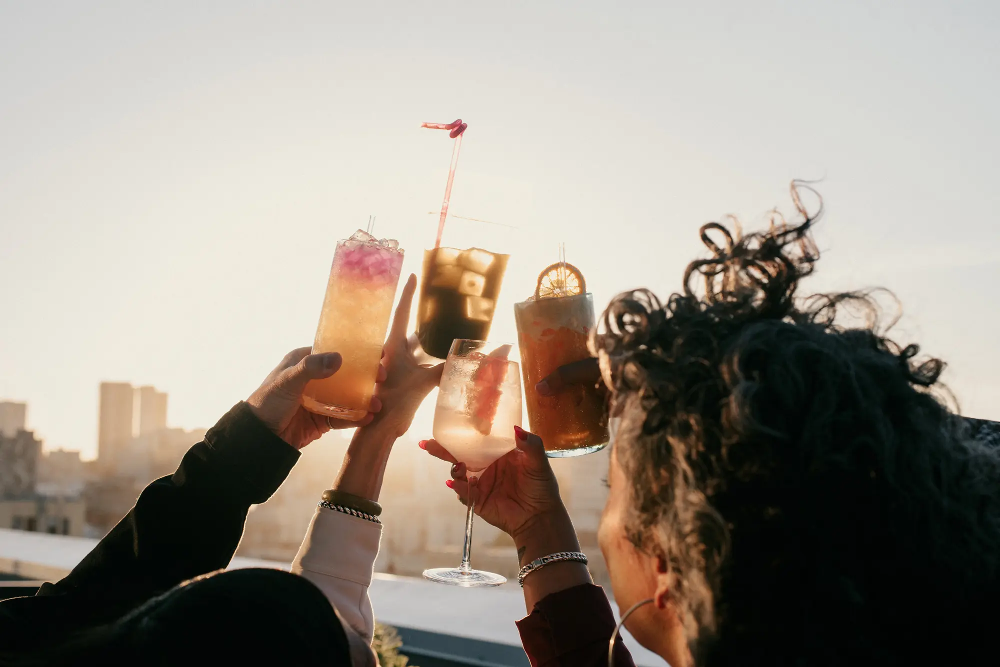 A group of people raise their glasses in joyful celebration and cheer together.