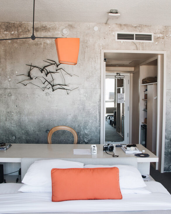 An artistic design adorns the wall just above the long table, accompanied by a chair.