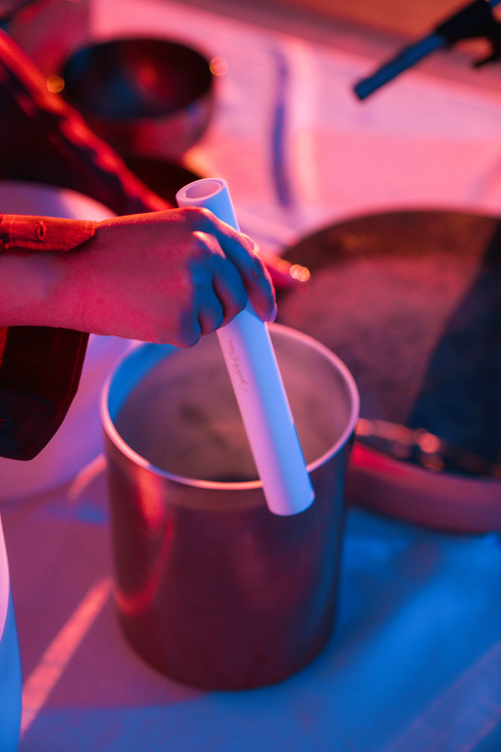 A hand creates music using a pipe and a small drum.