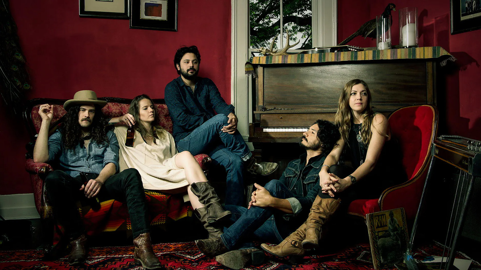 A group of people sits on a cozy sofa, enjoying their drinks together.