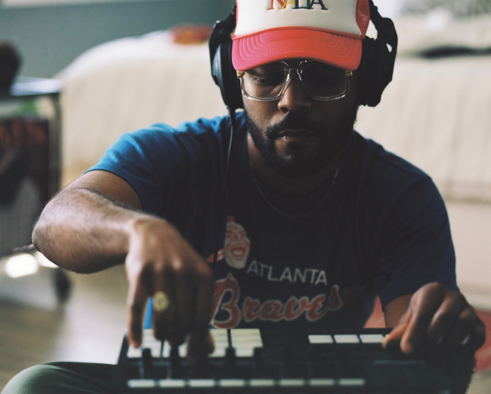 A DJ artist in a cape and headset adjusts his musical instrument.