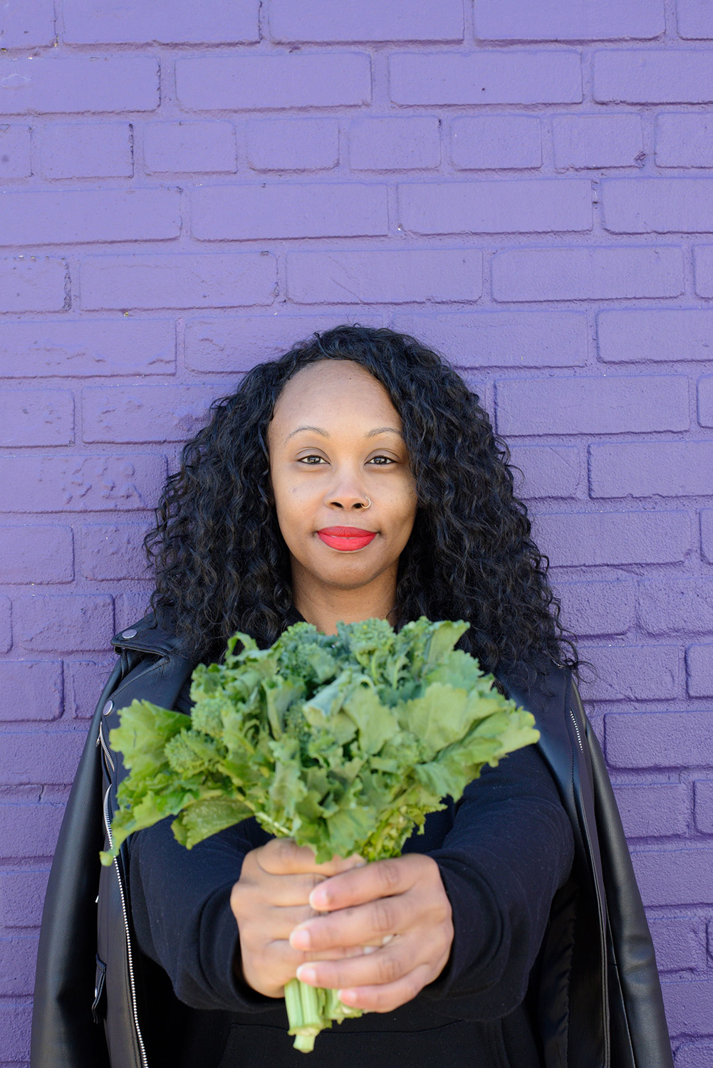 A portrait of Melissa L Jones holding a bunch of vegetable