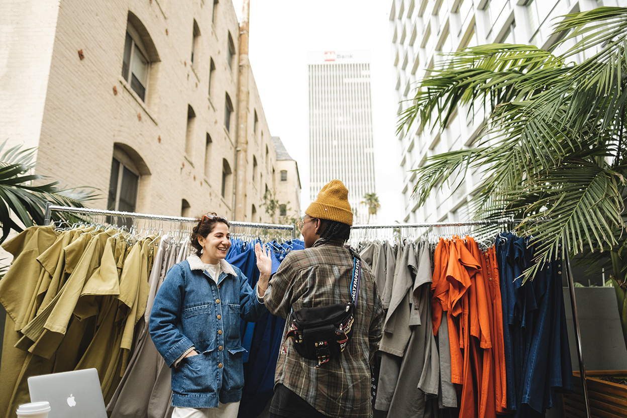 Two people talking in front of a clothing rack