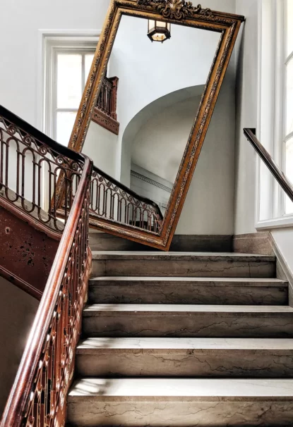 Picture of a antique wooden mirror kept on the staircase