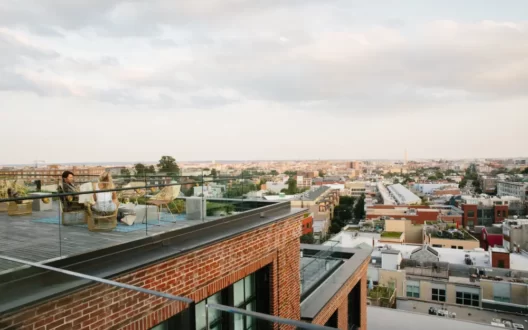 Picture of a balcony with two people sitting and talking along with city view