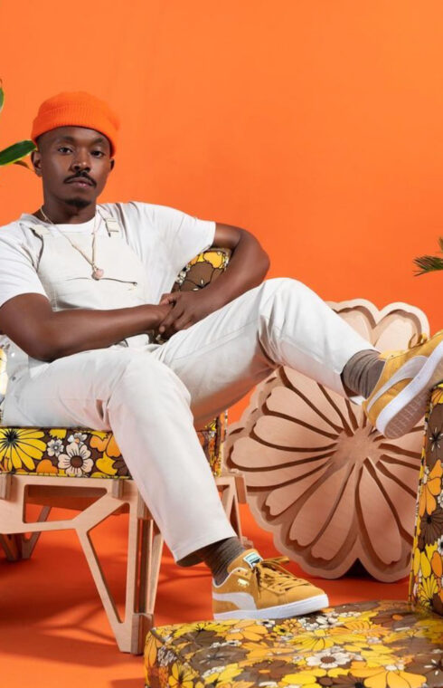 a person in white t-shirt, white pants, and orange hat lounging on a chair