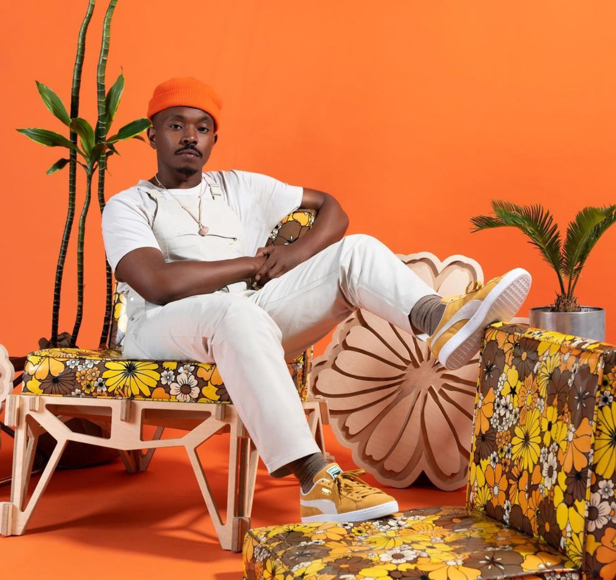 a person in white t-shirt, white pants, and orange hat lounging on a chair