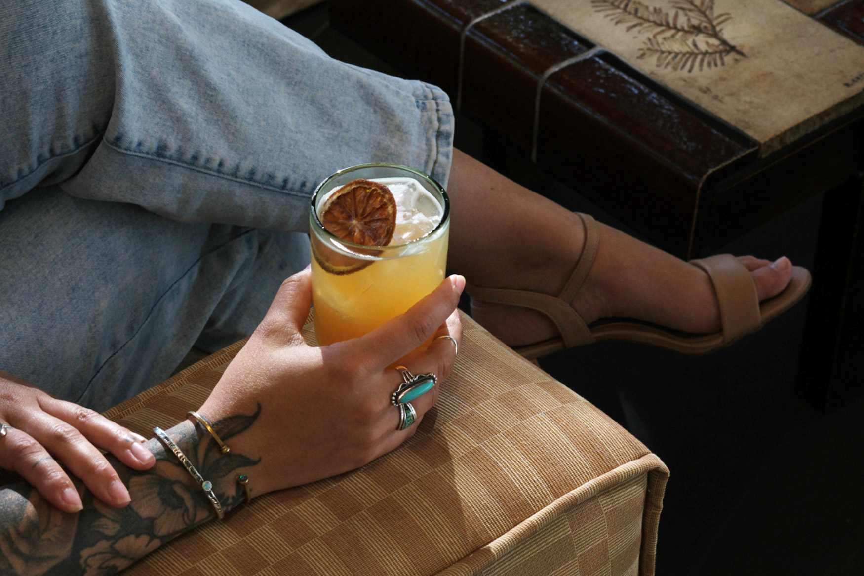 A person holding a glass of cocktail while sitting on a couch