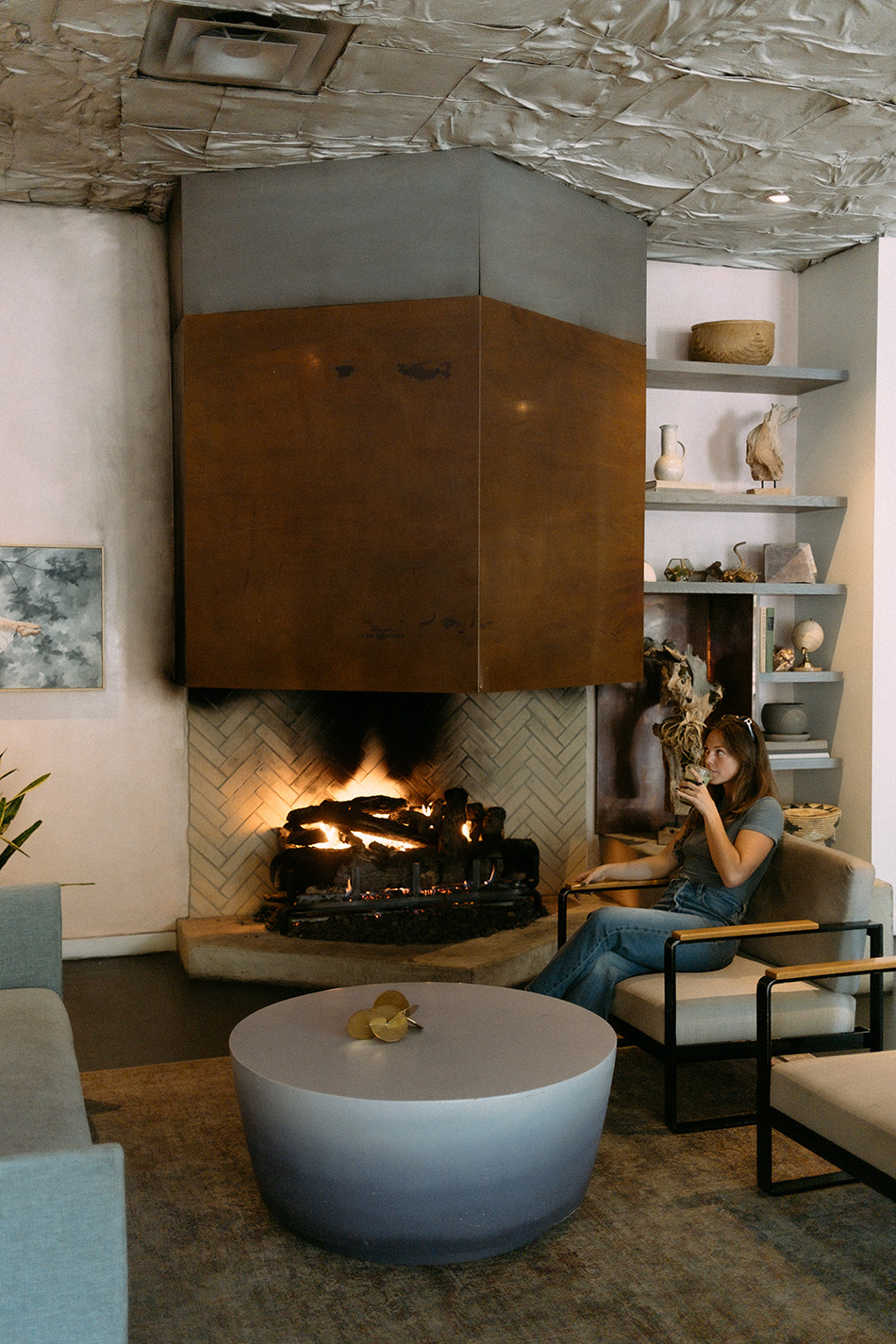 a person sipping on a cup of drink next to a fireplace