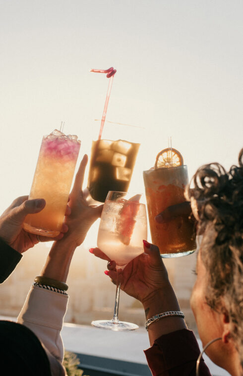 People raise their cocktail glasses in jubilation on the rooftop.