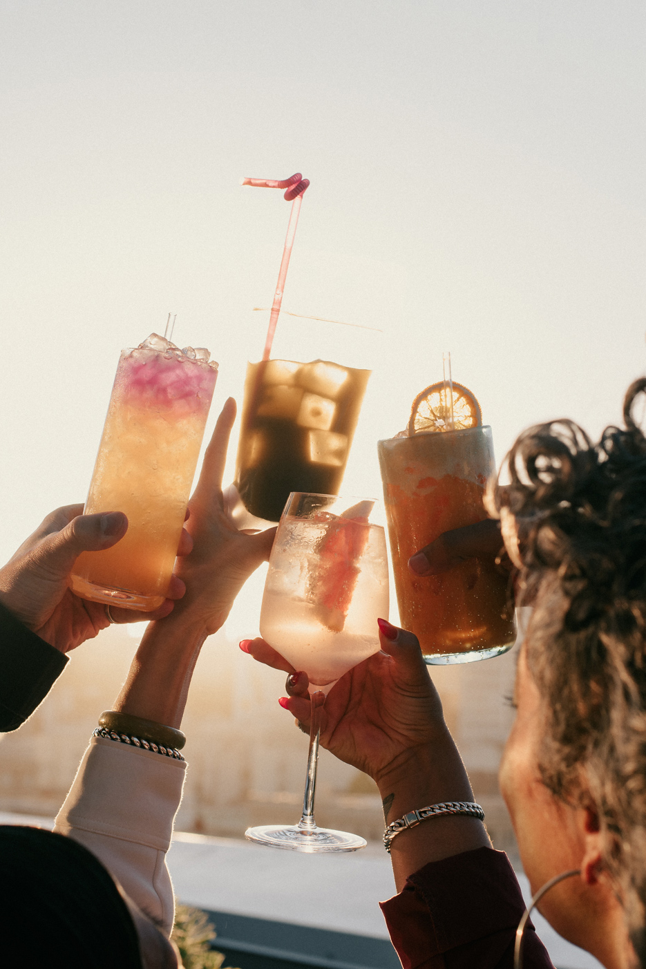 People raise their cocktail glasses in jubilation on the rooftop.