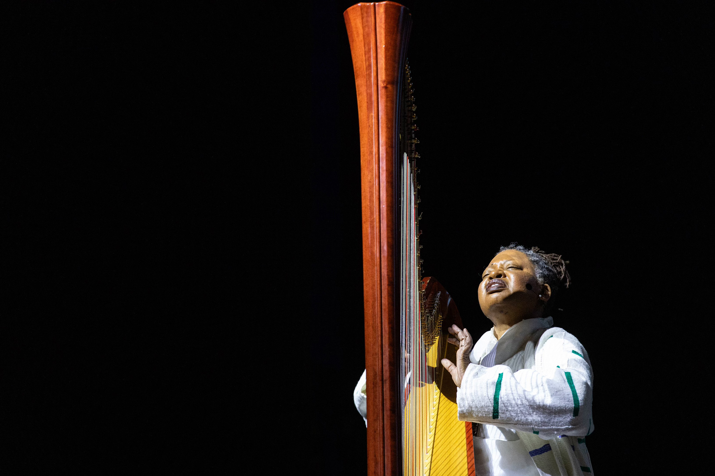 A portrait of Destiny Muhammad playing a harp